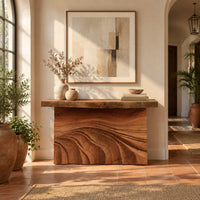 Console table with rough slab top and dune carved base in a bright entryway with arched windows and plants