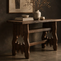Corner detail of rustic plank top console table with cutout slab legs and two cross rails beside wood, brass and linen samples
