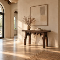 Rustic plank console table with thick legs and a jagged drip edge apron in a bright open plan entryway