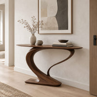 Oval top console table on a sweeping s curve pedestal base in a Scandinavian entryway with white walls