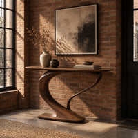 Oval top console table on a sweeping s curve pedestal base in an industrial loft entryway with exposed brick