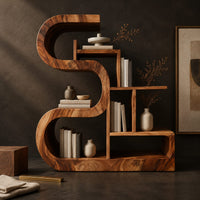 Corner detail of wooden bookshelf with a thick s shaped curve and stepped open shelves beside wood, brass and linen samples