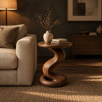 Side table with a twisting pedestal and a coiled loop base in a dark living room at golden hour
