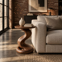 Side table with a twisting pedestal and a coiled loop base in an industrial loft living room with exposed brick
