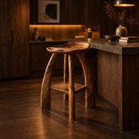 Saddle seat bar stool with curved legs and a low square shelf in an evening kitchen with walnut wall paneling