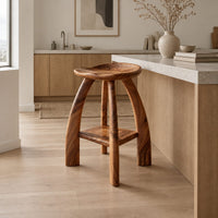 Saddle seat bar stool with curved legs and a low square shelf in a Scandinavian kitchen with white walls