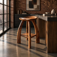 Saddle seat bar stool with curved legs and a low square shelf in an industrial loft kitchen with exposed brick