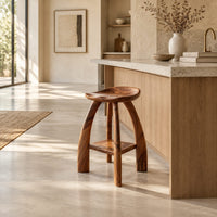 Saddle seat bar stool with curved legs and a low square shelf in a bright open plan kitchen