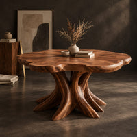 Corner detail of dining table with a scalloped edge top and a flared branching pedestal beside wood, brass and linen samples