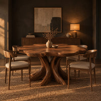 Dining table with a scalloped edge top and a flared branching pedestal in a dark dining room at golden hour