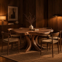 Dining table with a scalloped edge top and a flared branching pedestal in an evening dining room with walnut wall paneling