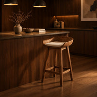 Bar stool with a scooped wooden seat and a cream cushion in an evening kitchen with walnut wall paneling