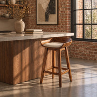 Bar stool with a scooped wooden seat and a cream cushion in an industrial loft kitchen with exposed brick