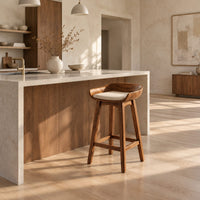 Bar stool with a scooped wooden seat and a cream cushion in a bright open plan kitchen