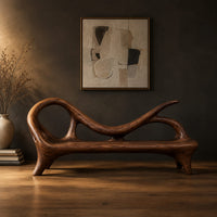 Bench with a looping scroll back and a flat seat on splayed legs in a dark studio against a charcoal plaster wall