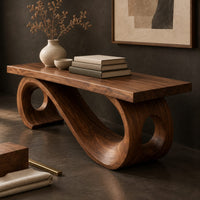 Corner detail of wooden bench with a thick plank seat on a flowing scroll shaped base beside wood, brass and linen samples