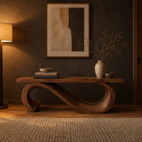 Wooden bench with a thick plank seat on a flowing scroll shaped base in a dark entryway at golden hour