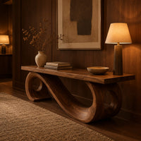 Wooden bench with a thick plank seat on a flowing scroll shaped base in an evening entryway with walnut wall paneling
