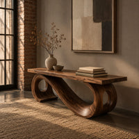 Wooden bench with a thick plank seat on a flowing scroll shaped base in an industrial loft entryway with exposed brick