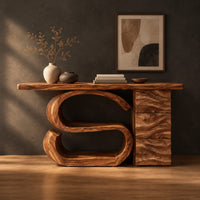 Console table with a large scroll base and a wave carved side column in a dark studio against a charcoal plaster wall