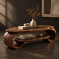 Corner detail of oval coffee table with scrolled end supports and a lower oval shelf beside wood, brass and linen samples