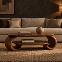 Oval coffee table with scrolled end supports and a lower oval shelf in a dark living room at golden hour