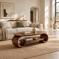 Oval coffee table with scrolled end supports and a lower oval shelf in a bright open plan living room