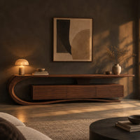 Tv stand with a sweeping scroll end and a three panel cabinet in a dark living room at golden hour