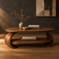 Oval coffee table with scrolled sides and a low shelf in a dark studio against a charcoal plaster wall