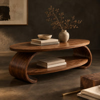 Corner detail of oval coffee table with scrolled sides and a low shelf beside wood, brass and linen samples