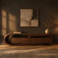 Low tv stand with a scroll end top, four front panels and wavy base in a dark living room at golden hour