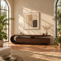 Low tv stand with a scroll end top, four front panels and wavy base in a bright living room with arched windows and plants