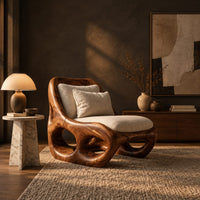 Sculpted wood accent chair with open loops in the base and loose cushions in a dark living room at golden hour