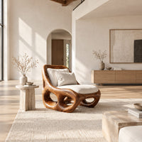 Sculpted wood accent chair with open loops in the base and loose cushions in a bright open plan living room