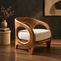 Barrel shaped chair with open oval cutouts and a cream seat cushion, three-quarter view showing the grain