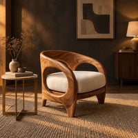 Barrel shaped chair with open oval cutouts and a cream seat cushion in a dark living room at golden hour