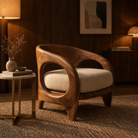 Barrel shaped chair with open oval cutouts and a cream seat cushion in an evening living room with walnut wall paneling