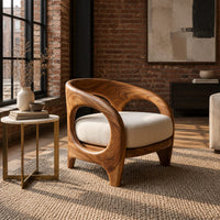 Barrel shaped chair with open oval cutouts and a cream seat cushion in an industrial loft living room with exposed brick