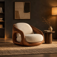 Barrel shaped wood chair with oval side openings and cream cushions in a dark living room at golden hour