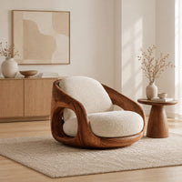 Barrel shaped wood chair with oval side openings and cream cushions in a Scandinavian living room with white walls