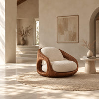 Barrel shaped wood chair with oval side openings and cream cushions in a bright open plan living room