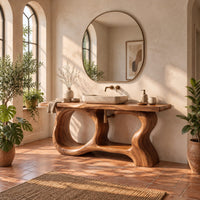 Open frame vanity with a freeform slab top and a sculpted looping base in a bright bathroom with arched windows and plants