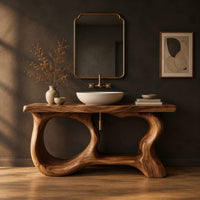 Freestanding vanity base with looping open legs and a thick wood slab top in a dark studio against a charcoal plaster wall