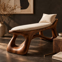Corner detail of sculpted bench with a cushioned seat and open loop legs beside wood, brass and linen samples