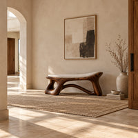 Sculpted bench with a cushioned seat and open loop legs in a bright open plan entryway