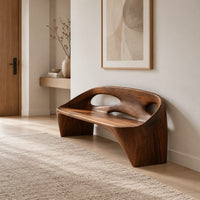 Sculpted bench with a cutout back and swept side legs in a Scandinavian entryway with white walls