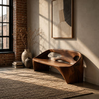 Sculpted bench with a cutout back and swept side legs in an industrial loft entryway with exposed brick