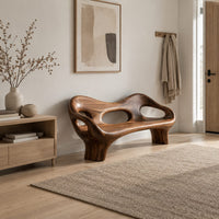 Sculpted wood bench with a low back and three oval openings in a Scandinavian entryway with white walls
