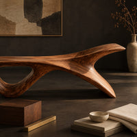 Corner detail of long low wooden bench with a triangular open leg and a swept tapered end beside wood, brass and linen samples