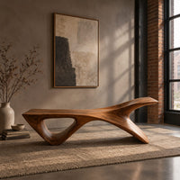 Long low wooden bench with a triangular open leg and a swept tapered end in an industrial loft entryway with exposed brick